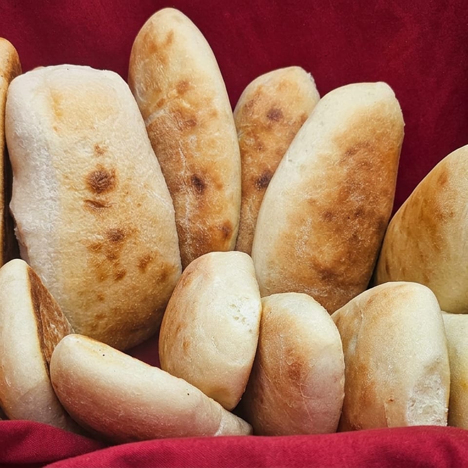 Assorted golden-brown baked breads arranged against rich red fabric.